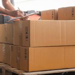 Worker inspecting stacked cardboard boxes on a wooden pallet Safe Packaging for Shipping and Logistics