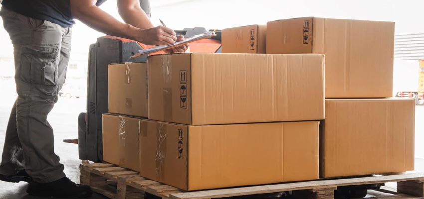 Worker inspecting stacked cardboard boxes on a wooden pallet Safe Packaging for Shipping and Logistics